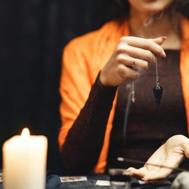 A woman performs a mystical pendulum ritual with burning candles.