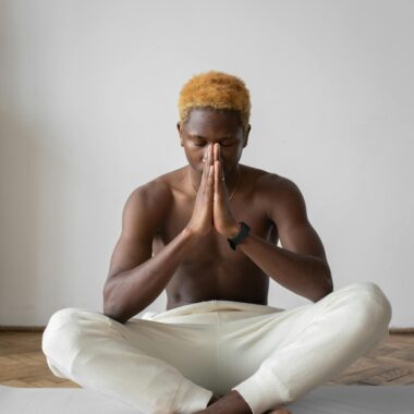 Shirtless black man practicing yoga indoors on a mat, focused and meditating.